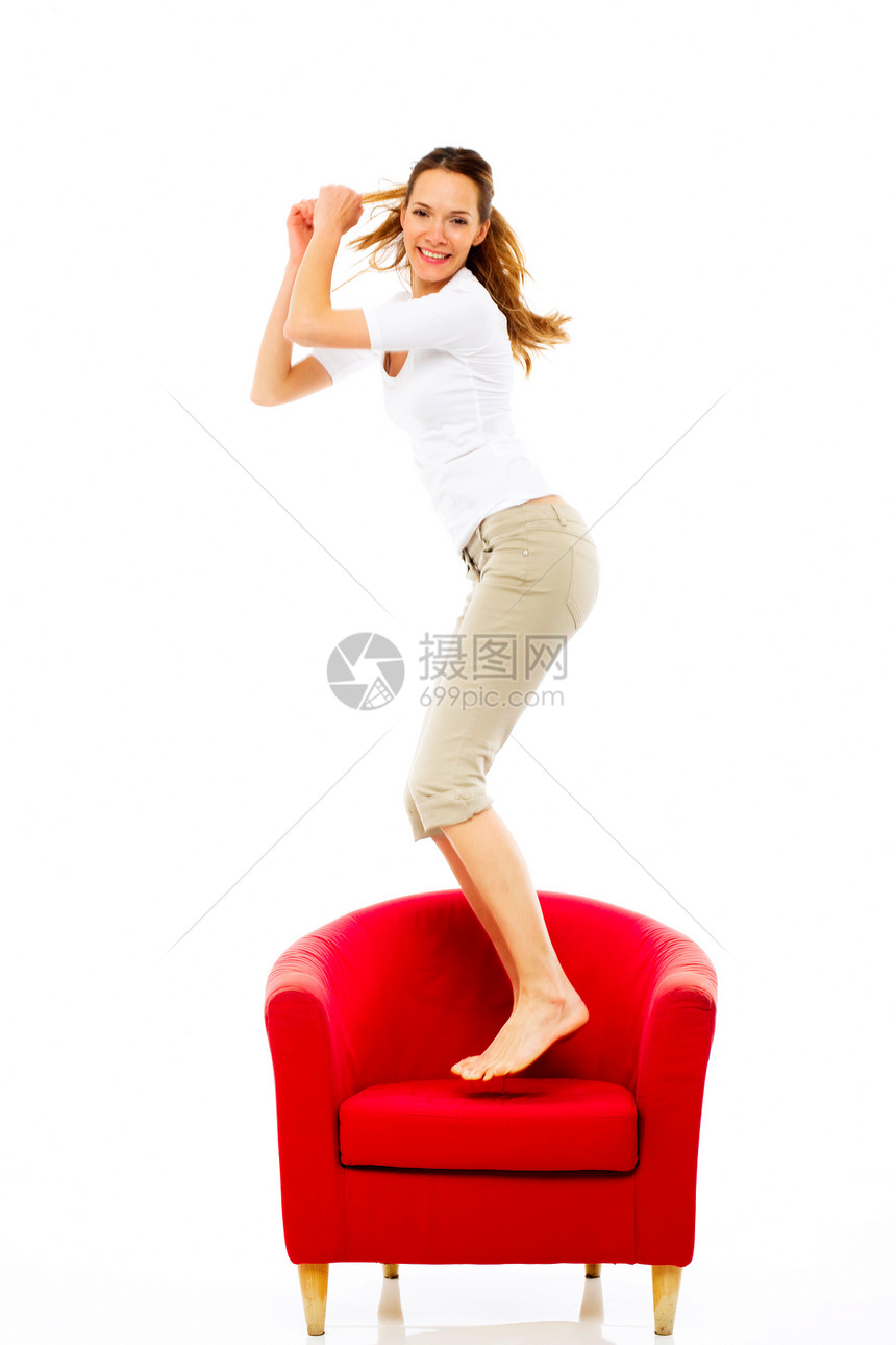 年轻女子在白人背景演播室 跳到椅子上图片