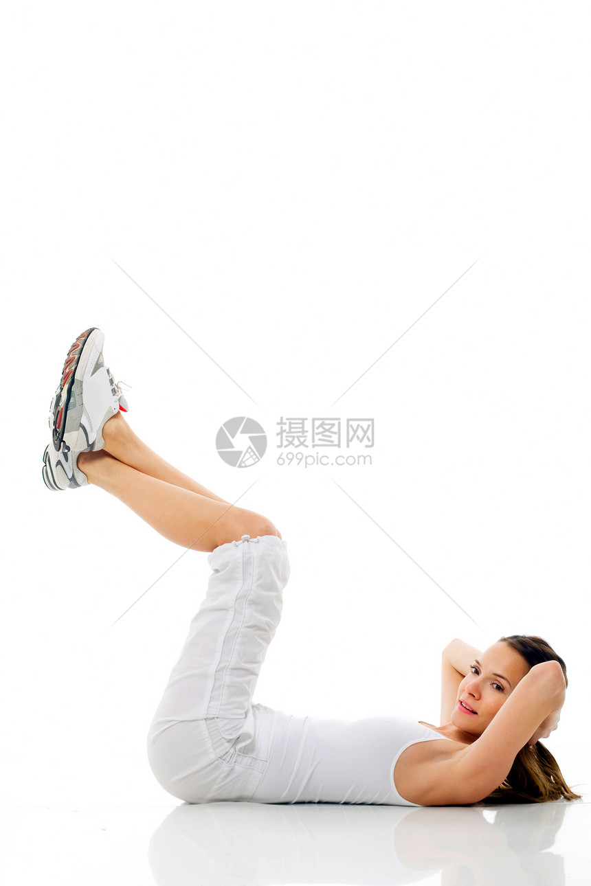 年轻女子在白背景演播室做体操娱乐运动鞋女士双腿女性腹肌成人运动装器材年轻人图片