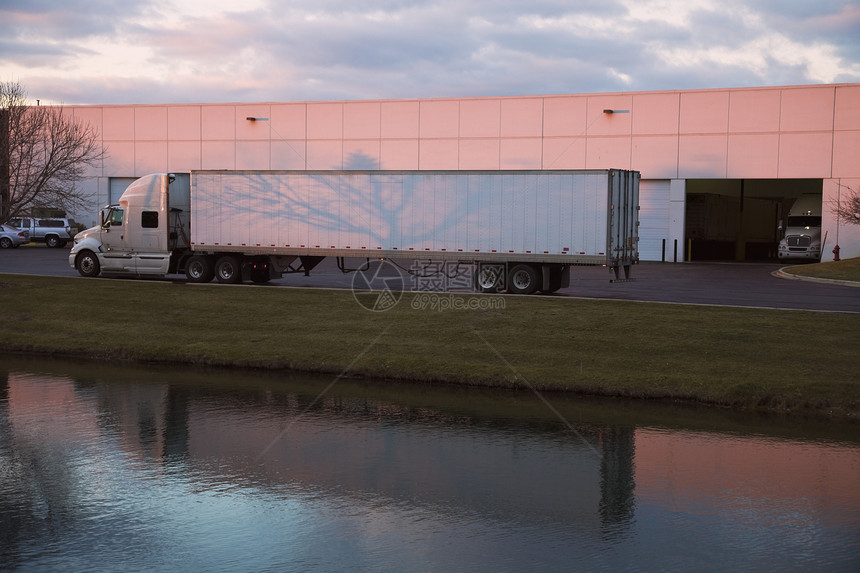 半卡车离开基地工业仓库运输白色日落反射天空送货船运图片