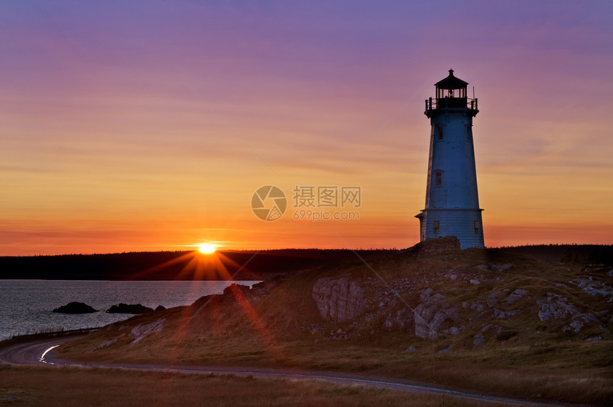 清晨日出时的灯塔日落红色太阳光海岸线海岸紫色黄色蓝色海洋太阳图片