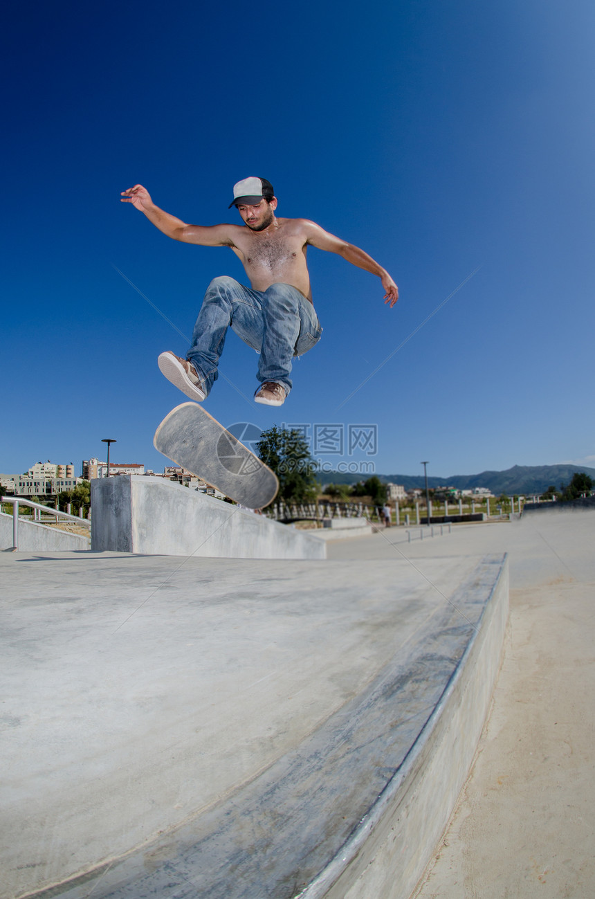 滑板机玩翻转把戏滑板街道乐趣文化溜冰者男人活动蓝色岩石青年图片