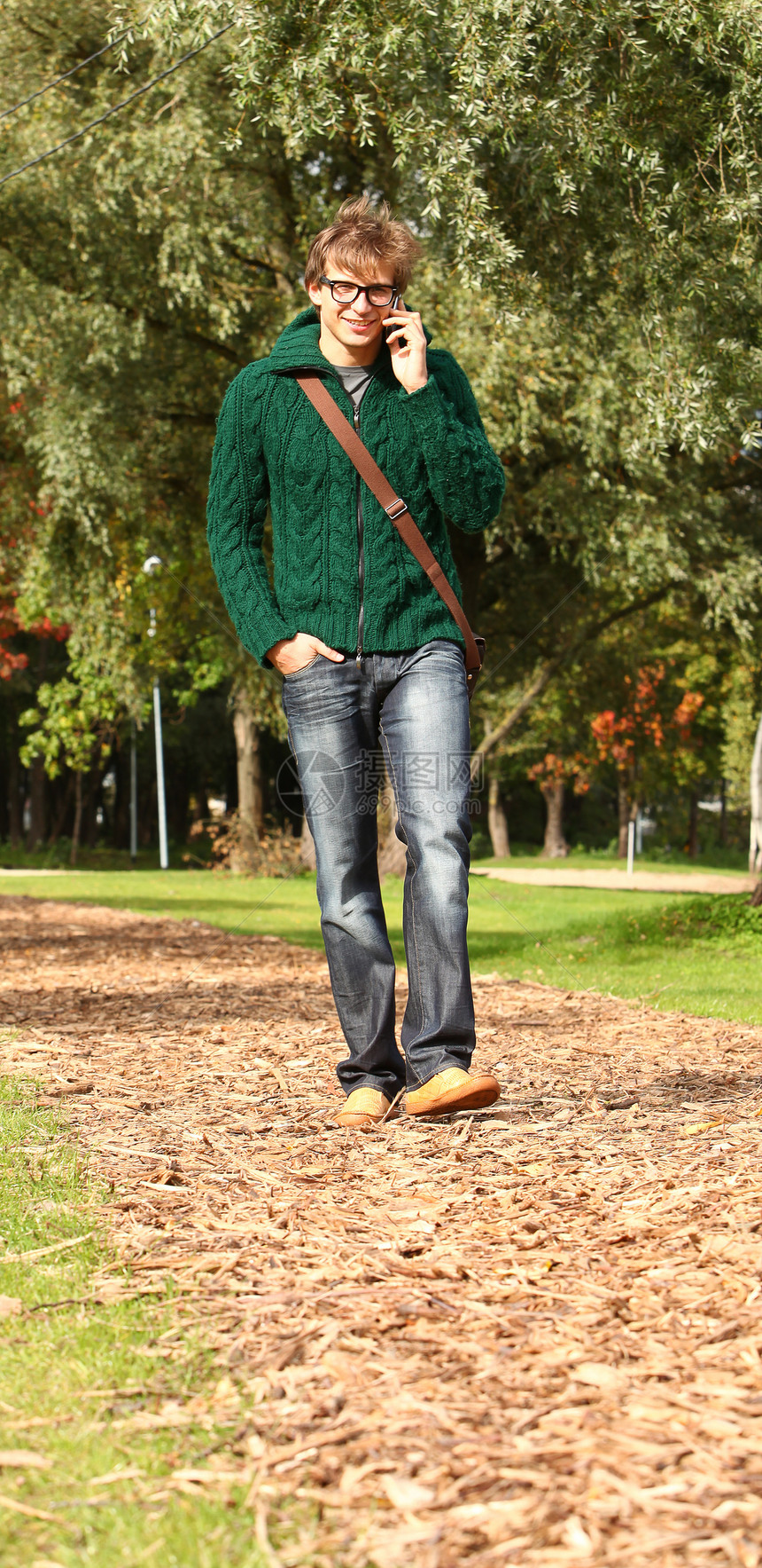 在公园里拿着手机走路的帅哥学生季节树叶晴天男人微笑照片衣服青年男性图片