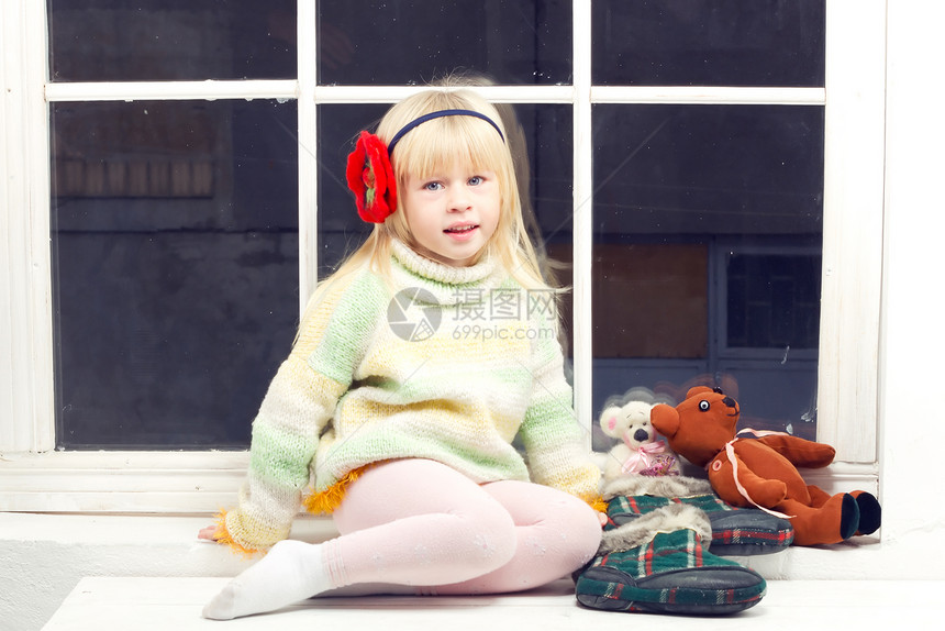 穿着毛衣的金发女孩窗户头巾乐趣童年编织女性花朵季节玩具眼睛图片