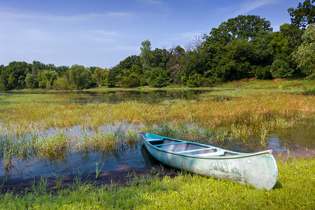 明尼苏达州池塘上的独木舟蓝色树木阳光娱乐自然海岸场景蓝天绿色天空背景