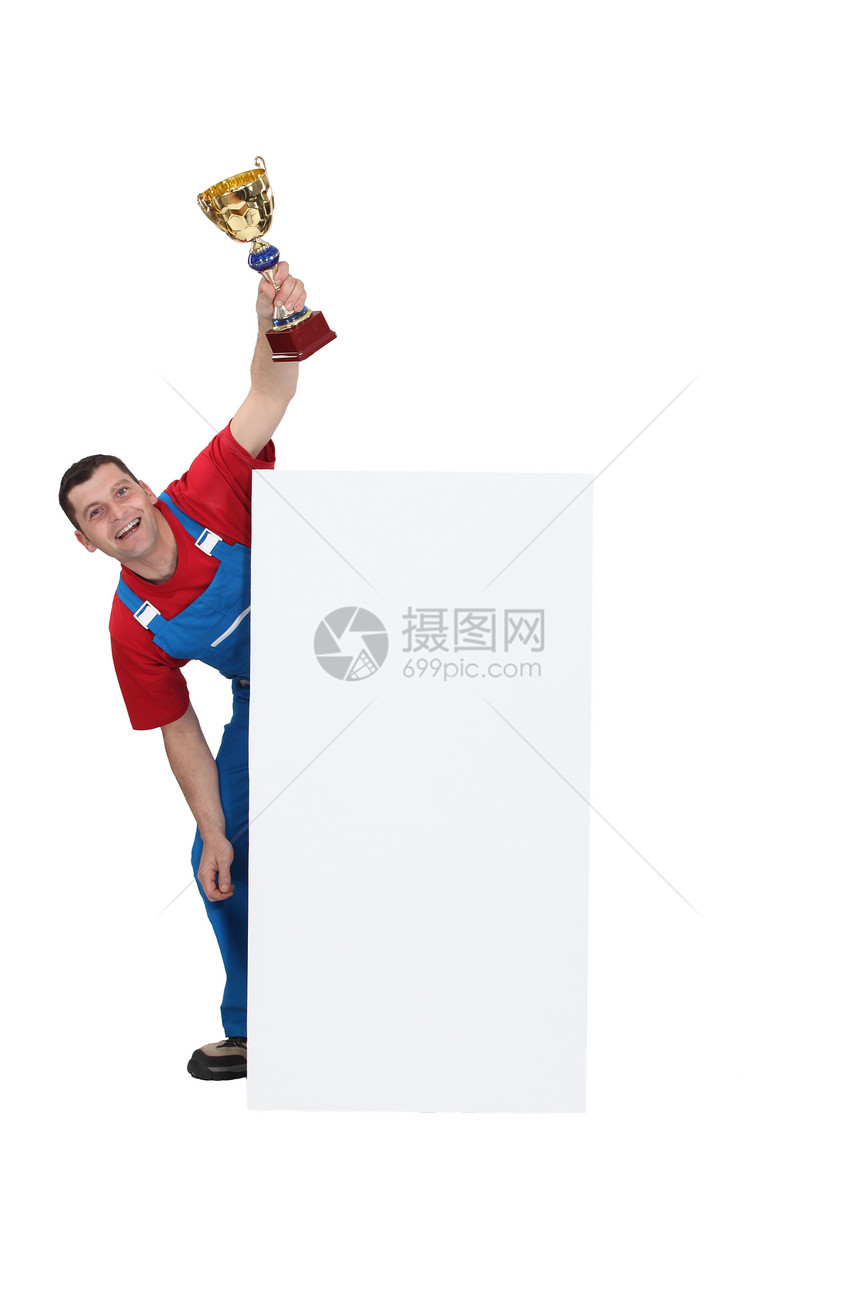 手工业工人拿着奖杯时 用空白海报站着图片