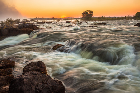 维多利亚瀑布的白水急流激流日落瀑布溪流水域橙子野生动物岩石河岸边缘背景图片
