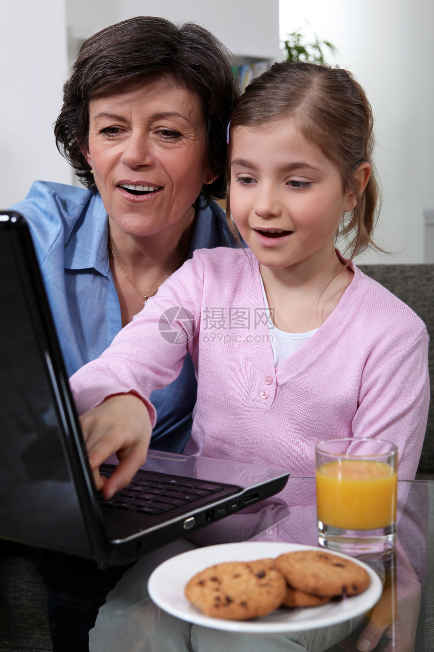 年幼的孩子和她祖母一起看笔记本电脑图片