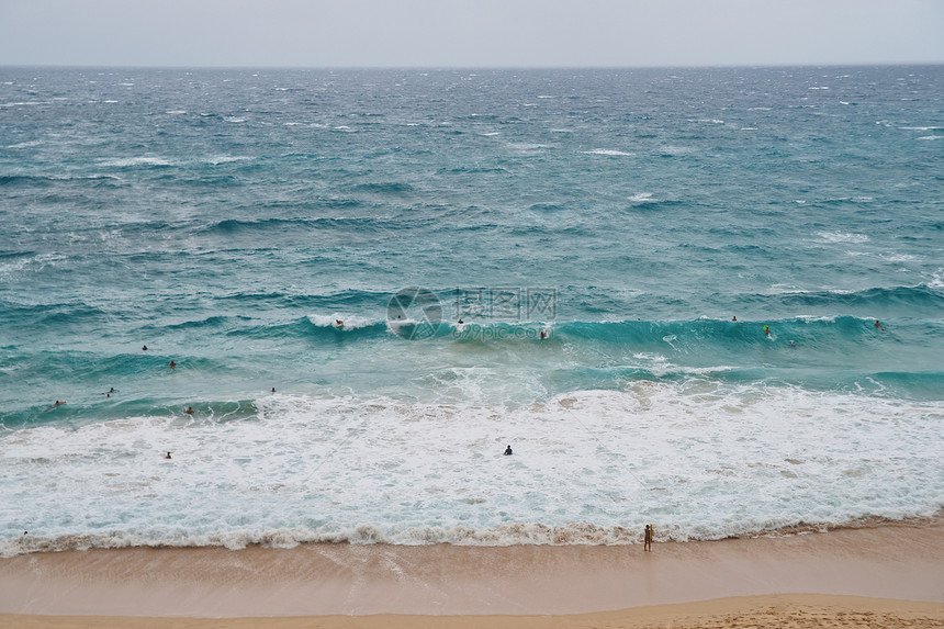 乘坐奥胡岛海滩海浪的拥挤冲浪者图片