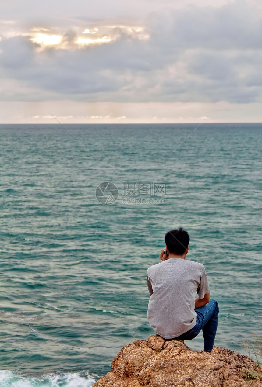 一个人坐在岩石上看着大海时图片