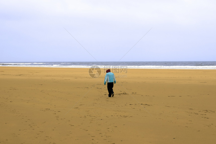 单身女孩在沙滩上与寒风相对图片