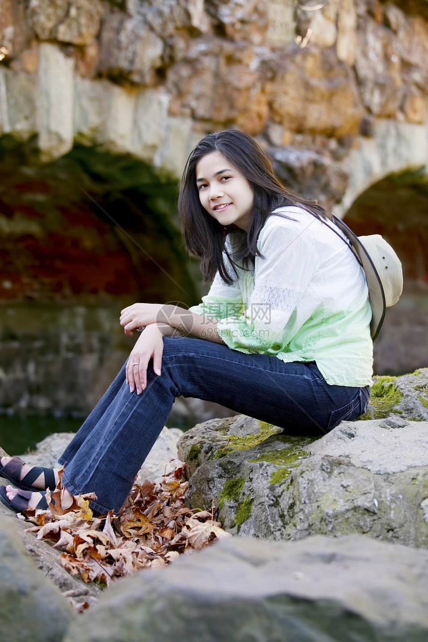 双种族少女通过石桥在岩石上放松图片
