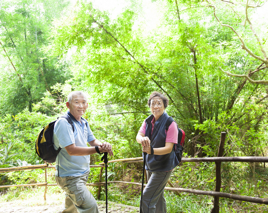 以竹子背景为本的高级夫妇徒步旅行图片