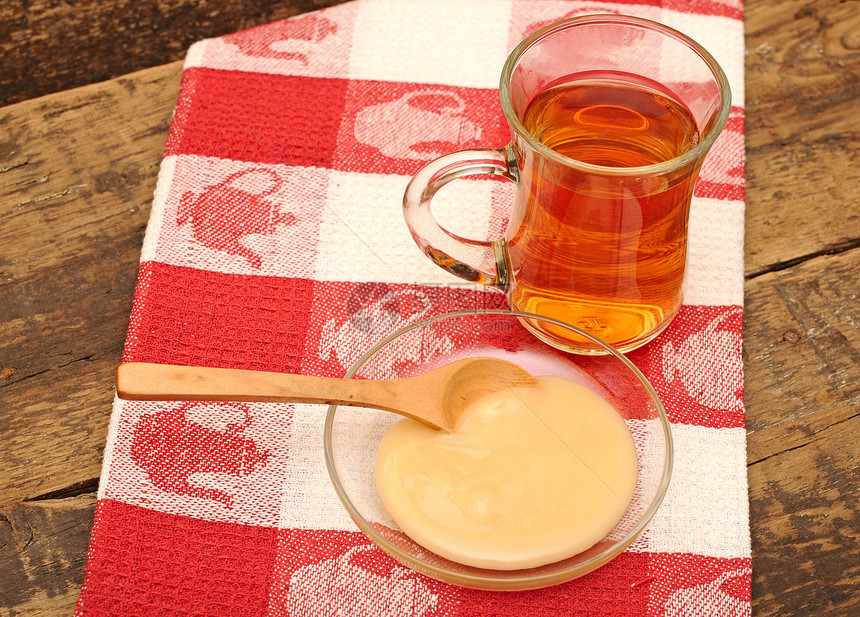 彩色餐巾纸上加蜂蜜的一杯茶早餐饮食液体水果蜂蜜瓶子橙子木头餐厅水滴图片