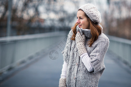 身穿温暖羊毛衣的年轻女子天气女士衣服开襟衫羊毛头发手套树木女性快乐背景图片