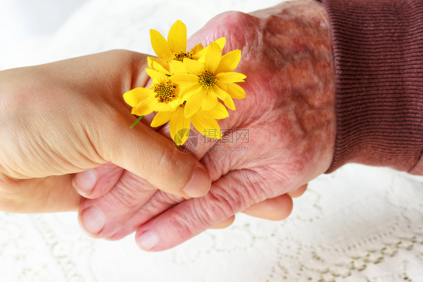 高级和年轻女性握手帮助黄色老年长老友谊手指服务祖母奶奶毯子图片