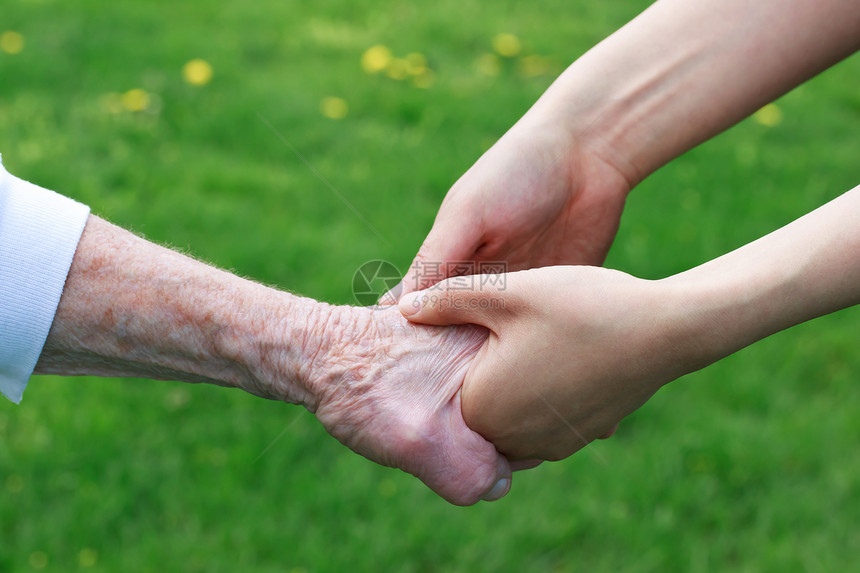 高级和青年妇女握手长老帮助老年女性家庭老化公园女士绿色祖母图片