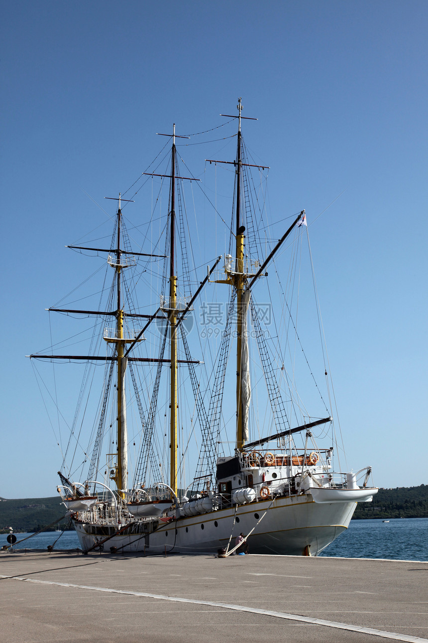 码头的帆船蓝色甲板绿色桅杆海岸港口白色支撑船尾天空图片