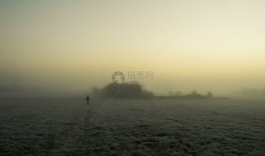 清晨在冰冻的田地上 在雾中行走的人的休眠图片