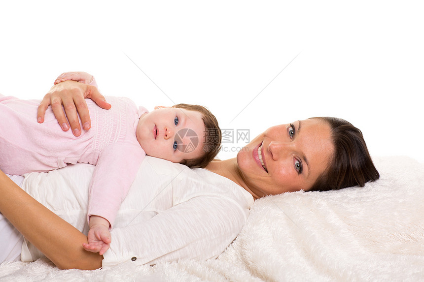 婴儿女孩和母亲在白毛皮上幸福地躺在一起家庭女性快乐妻子女士婴儿享受棉被工作室毯子图片