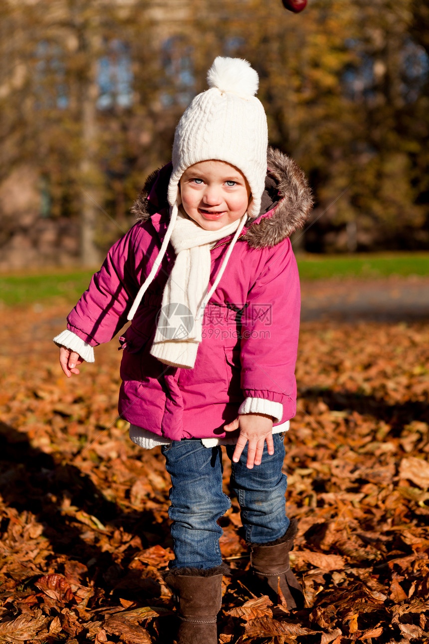 秋天在户外玩耍的可爱女孩橙子童年孩子闲暇婴儿季节公园幸福围巾活动图片