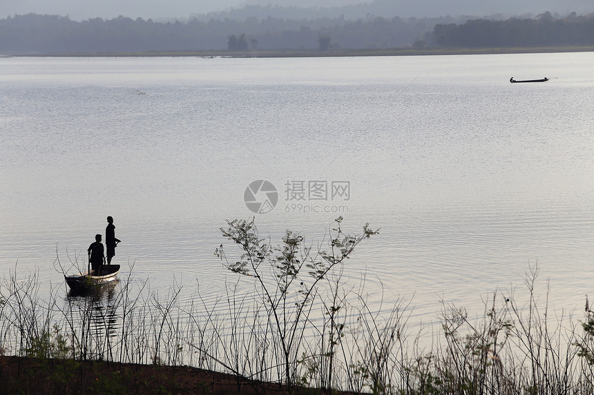 湖边木船上渔民的轮廓日落闲暇乐趣家庭风景场景活动爱好发动机反射图片