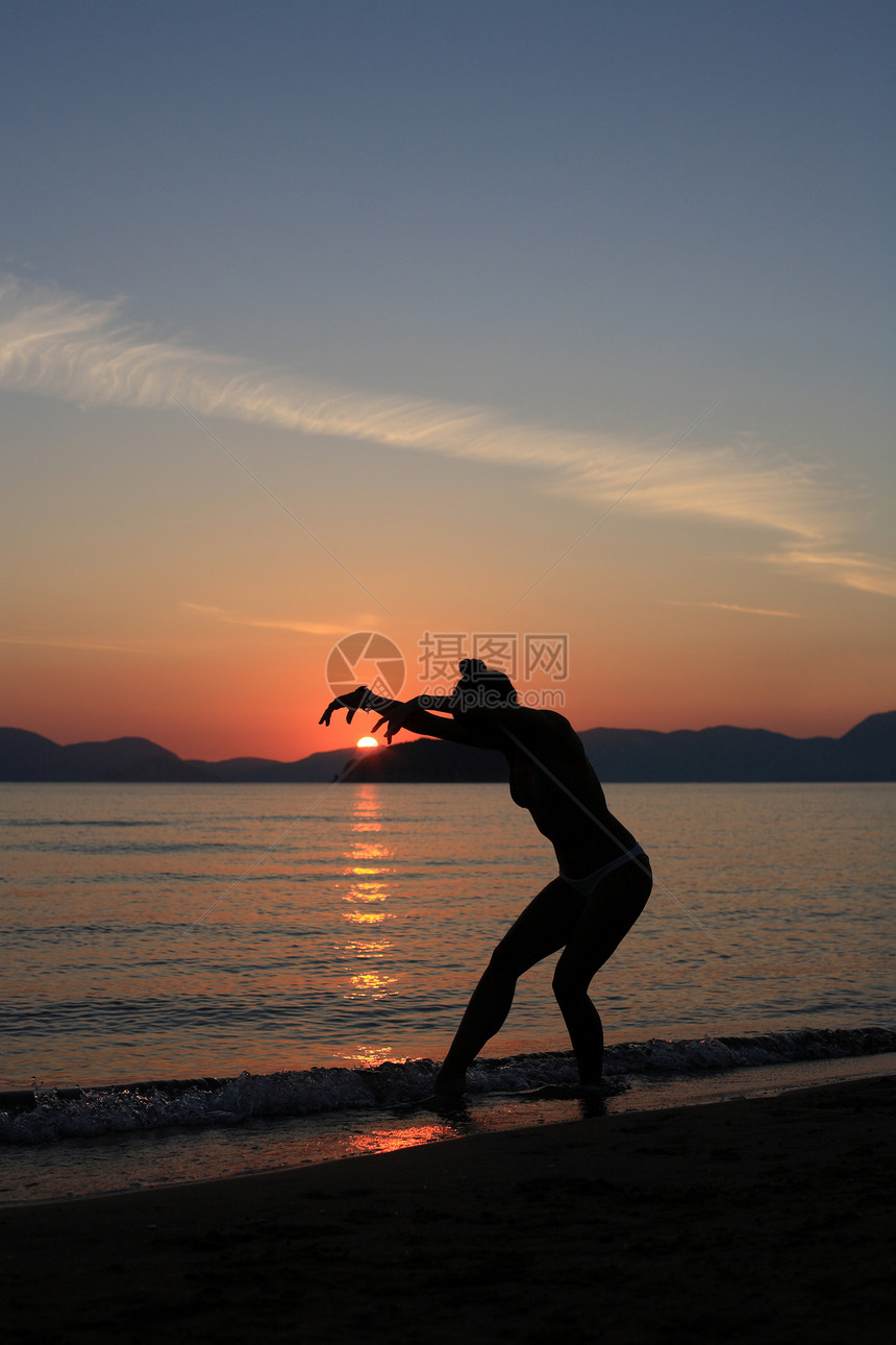 海滩上舞女的背影蓝色帽子舞蹈家女士天空衣服女性旅行姿势太阳图片