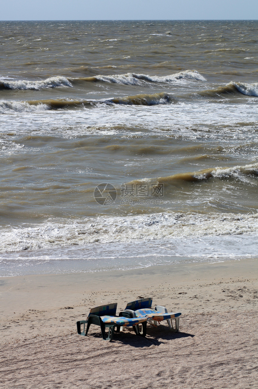 在海浪背景下的两张空塑料甲板椅上图片