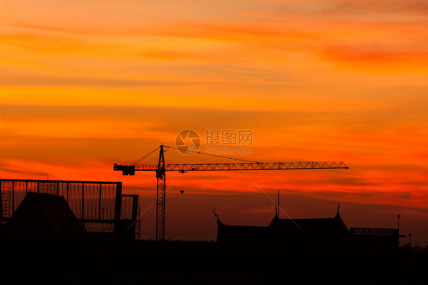 工业建造起重机和日出时建筑住房工人建筑工人脚手架日落橙子天空生长工程太阳图片