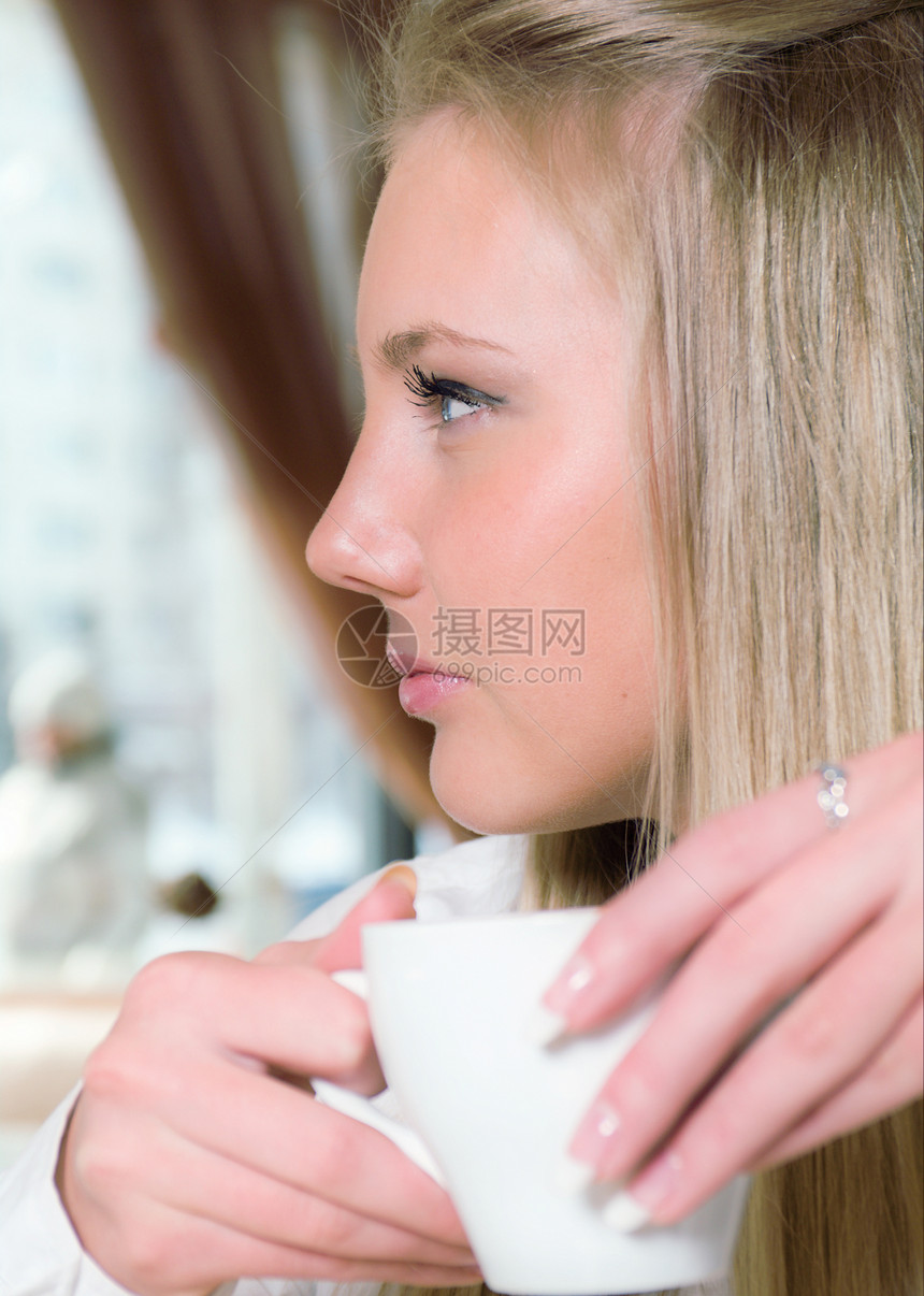 女人拿着一杯热饮微笑乐趣餐厅女性享受咖啡女士金发女郎女孩图片