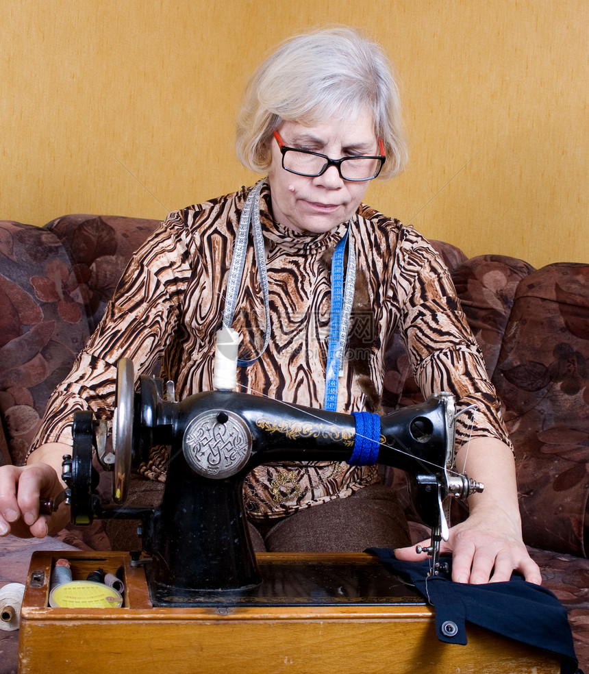在家使用缝纫机的老年妇女图片