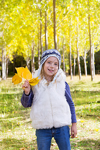 秋天的童女儿童 在阴花林中 黄色落叶手握着孩子蓝色女孩金发季节树叶花园女性树木快乐背景图片