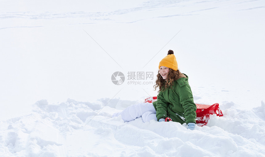 雪地上坐雪雪橇的女孩图片