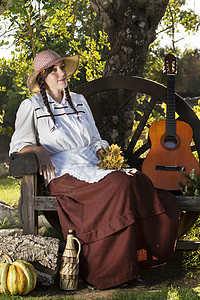 农村的漂亮女孩怀旧古董帽子长椅女孩公园红色吉他梦幻白色背景图片
