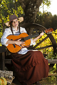 农村的漂亮女孩古董白色红色女士稻草女孩长椅吉他裙子梦幻背景图片