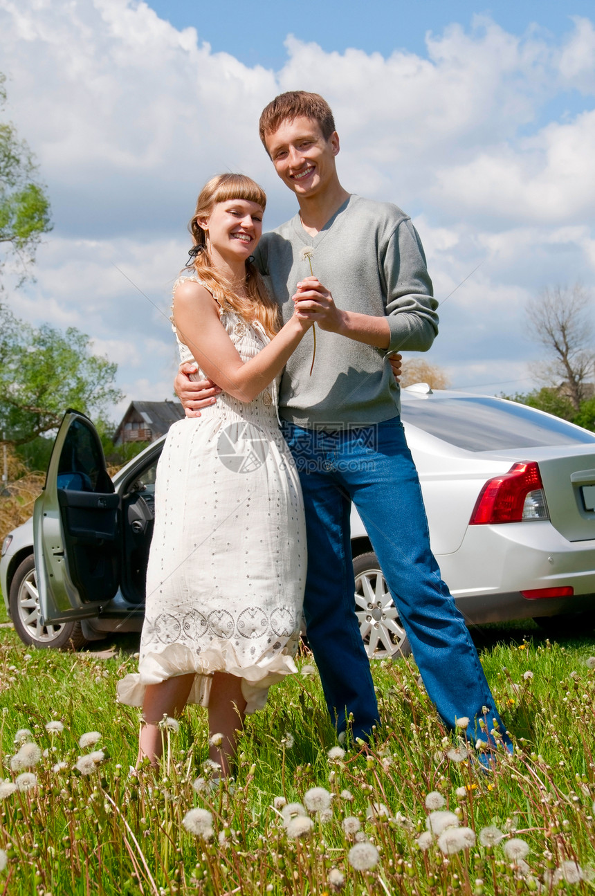 坐在车旁边的一对快乐的年轻夫妇图片