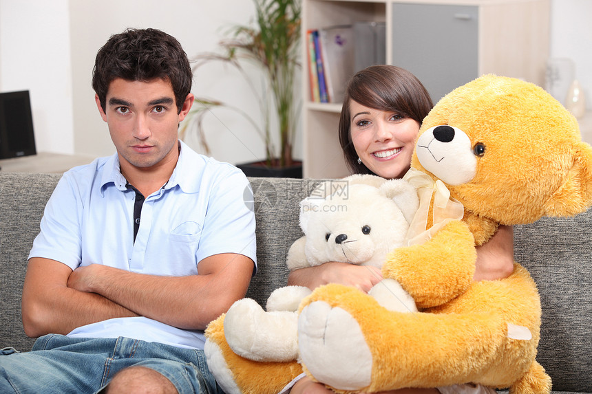 在沙发上挂着泰迪熊的年轻夫妇图片