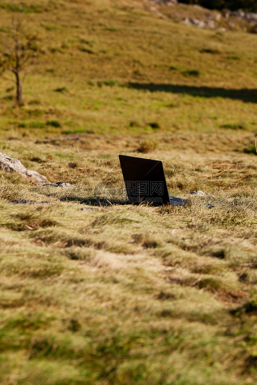 站在山坡草地上的笔记本电脑图片