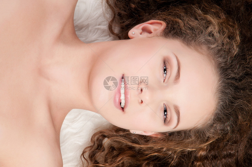 穿着完美卷发的女孩 躺在毛皮床上头发青少年快乐牙齿治疗化妆品眼睛肩膀发型说谎图片