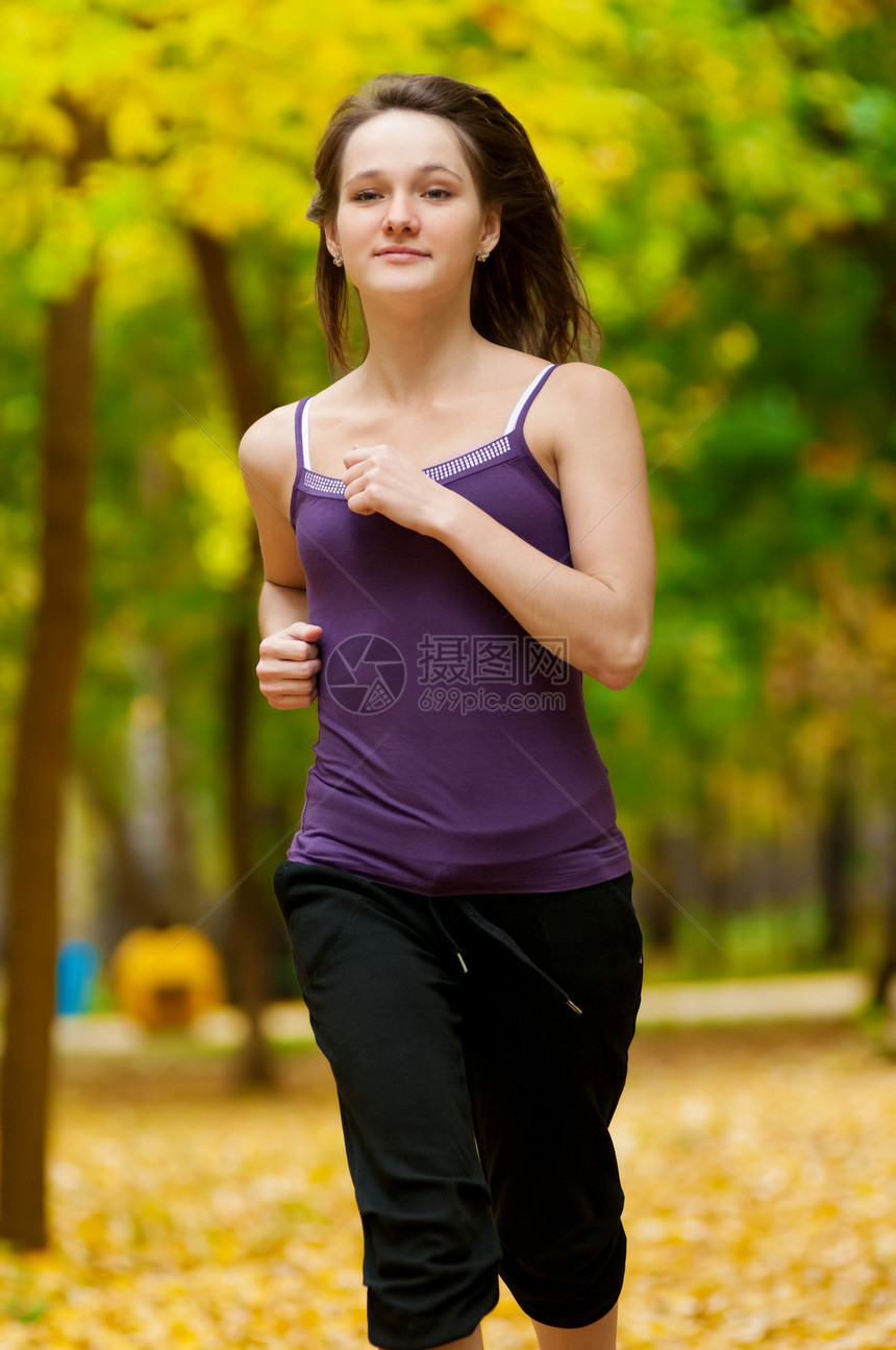 一个年轻女孩在秋天公园奔跑叶子闲暇寒冷活力女性运动员成人公园森林运动装图片
