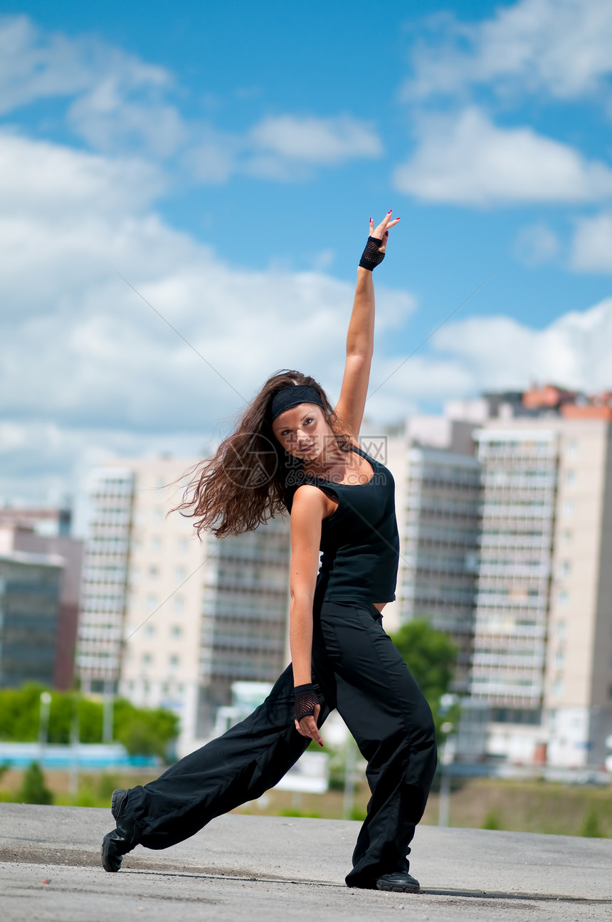 美丽女孩在城市风景中现代舞蹈风格街道快乐舞蹈家女士头发运动员成人女性天空特技图片