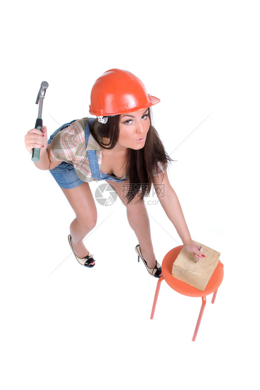 穿着橙色头盔锤钉子的年轻情感女性工具短裤深色指甲凳子蓝色木头产业橙子热情图片