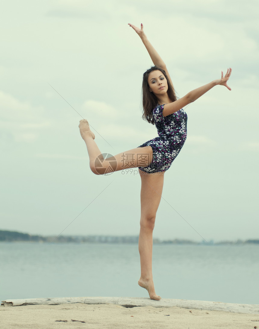 年轻体操运动员女孩在海滩上跳舞训练青少年海洋幸福女性孩子天空生活丝带运动图片