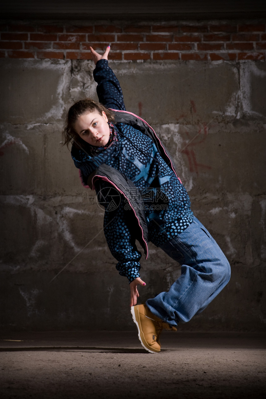 在砖墙上跳现代风格的Hipop舞者演员说唱蓝色青少年夜生活靴子特技霹雳舞牛仔裤街道图片