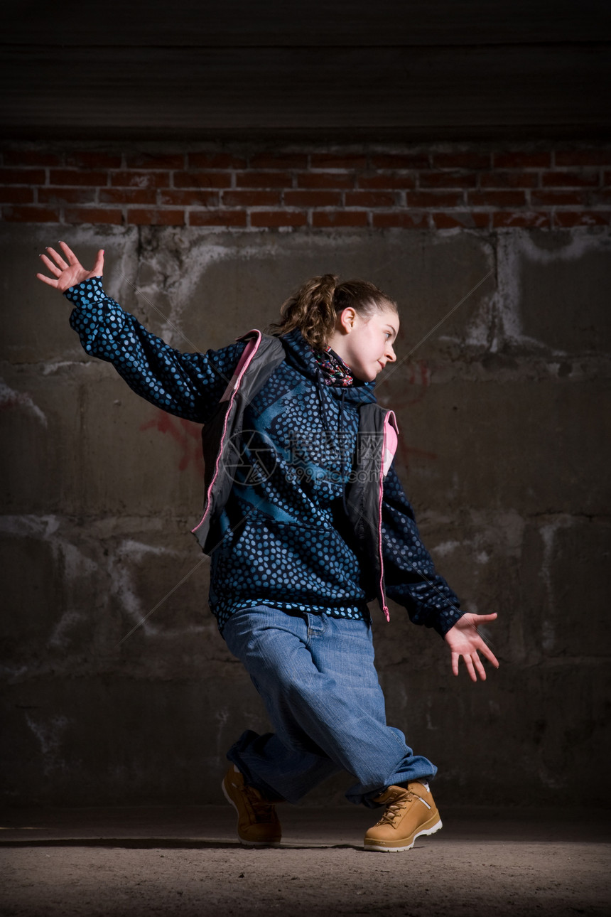 在砖墙上跳现代风格的Hipop舞者特技蓝色衣服情感说唱女孩靴子霹雳舞街道培训师图片