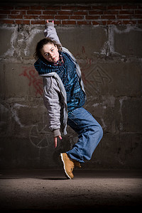 hipop在砖墙上跳现代风格的Hipop舞者舞蹈家衣服说唱运动女孩霹雳舞培训师牛仔裤街道特技背景