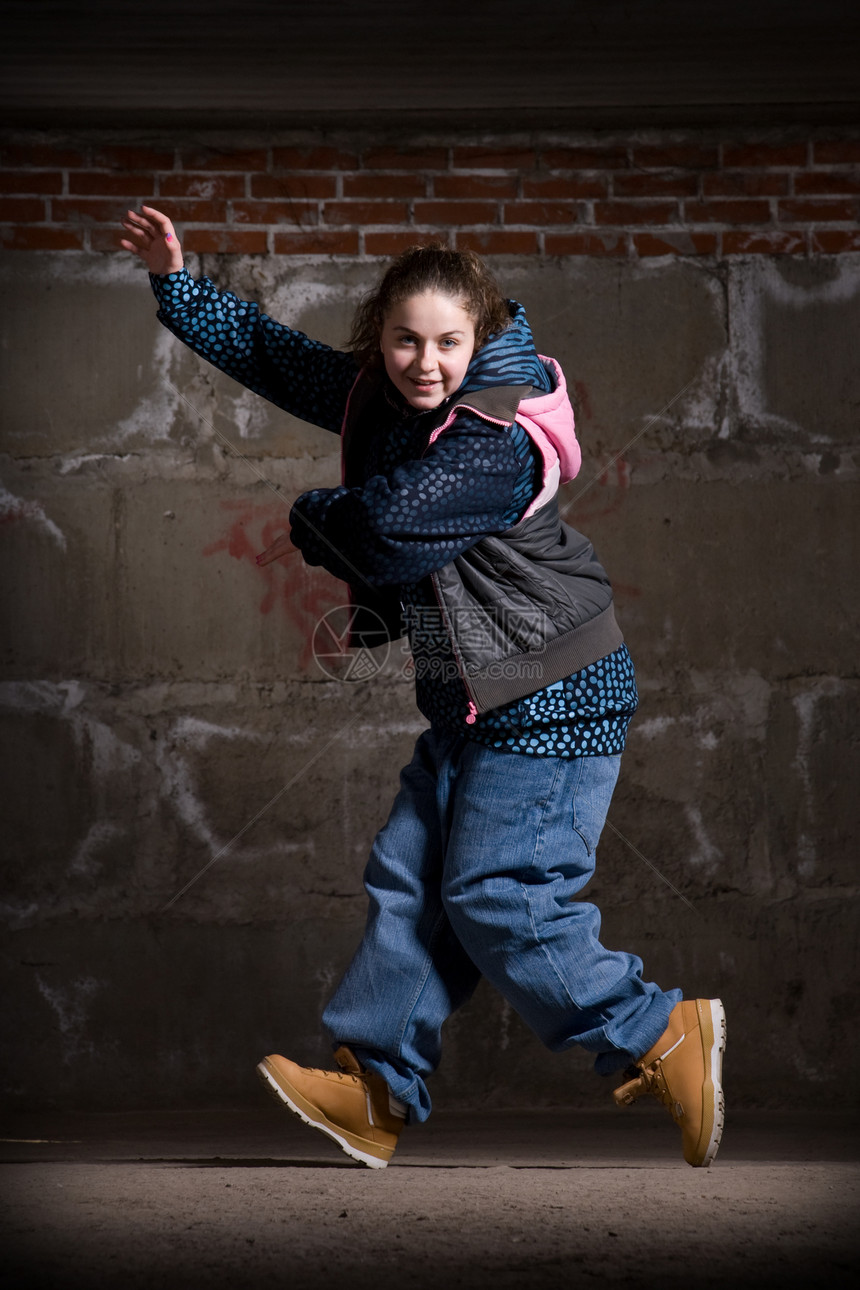 在砖墙上跳现代风格的Hipop舞者街道说唱衣服靴子运动特技演员夜生活舞蹈家黑发图片