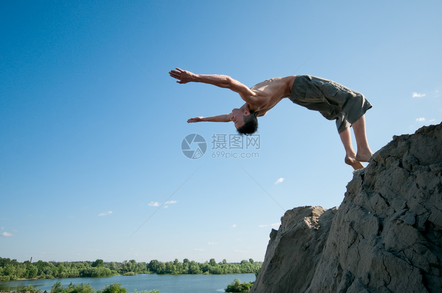 兴奋的年轻人在空气中跳跃男生太阳岩石蓝色男性自由飞跃悬崖情感快乐图片