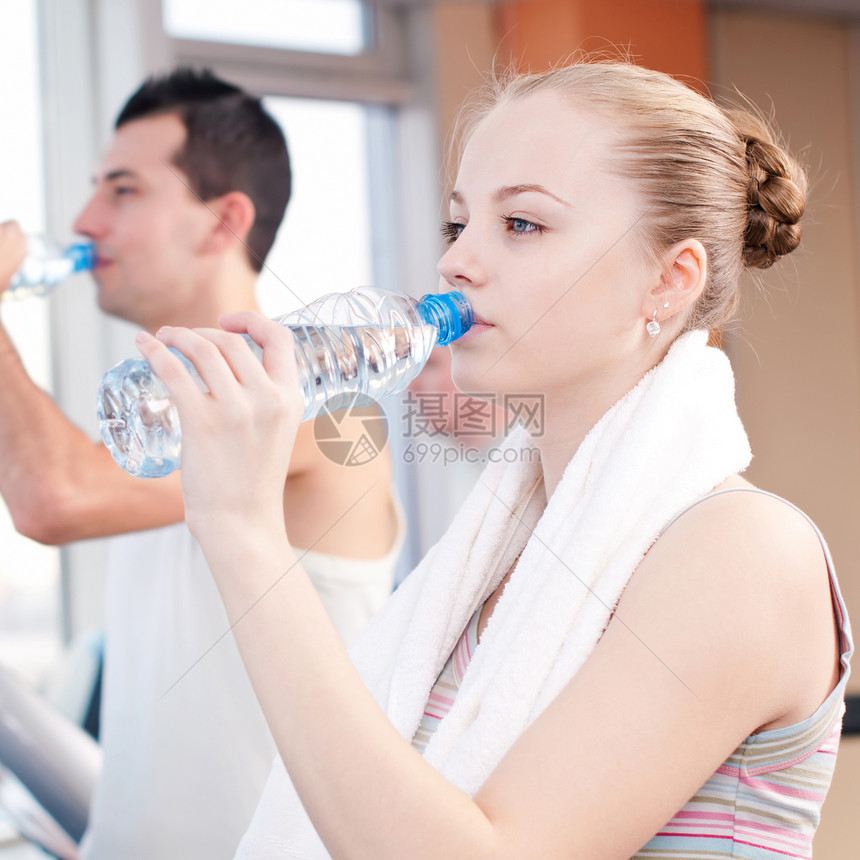 在体育馆运动后饮用饮用水的男女运动装活力健身房闲暇跑步机瓶子俱乐部毛巾跑步有氧运动图片