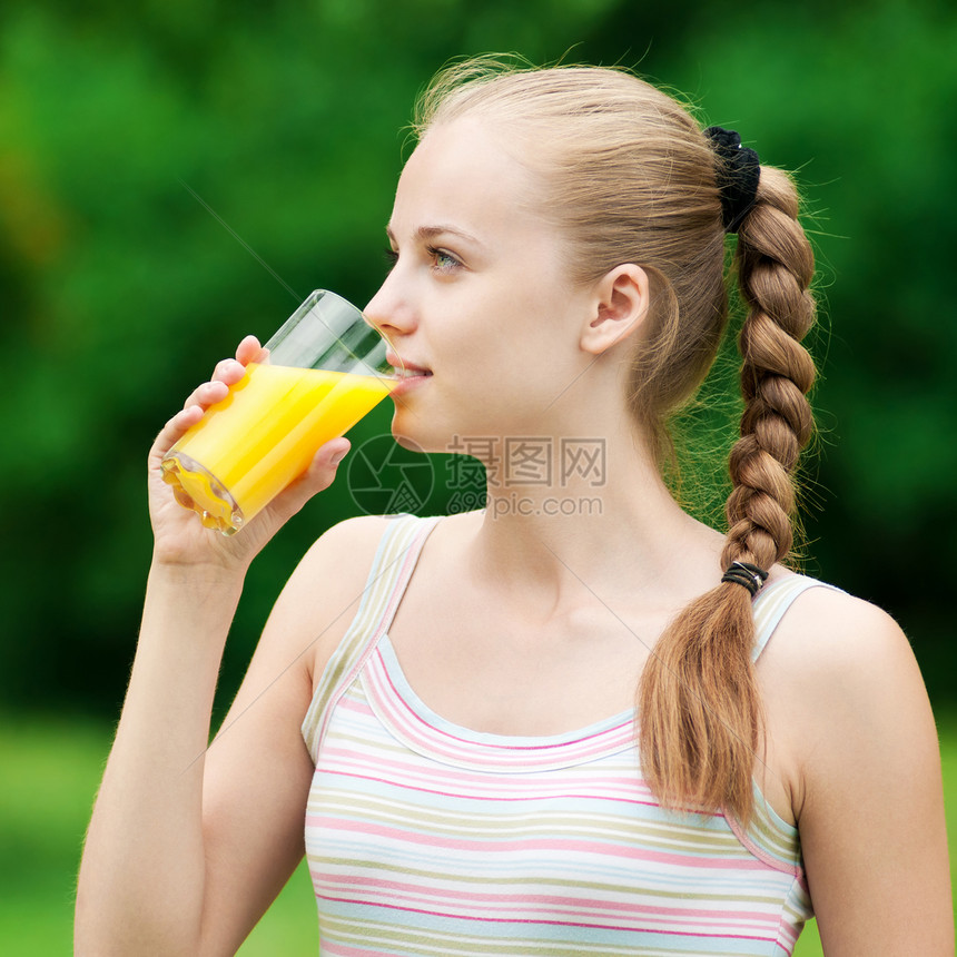 年轻女孩喝橙汁 外门口渴水果运动装玻璃福利卫生乐趣训练火车公园图片