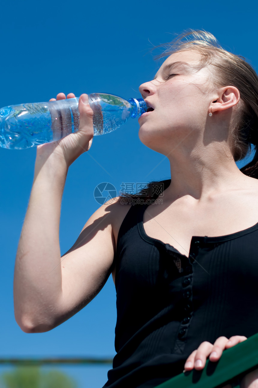 年青妇女锻炼后饮用饮用水成人女孩瓶子蓝色天空女士女性活力深色青少年图片